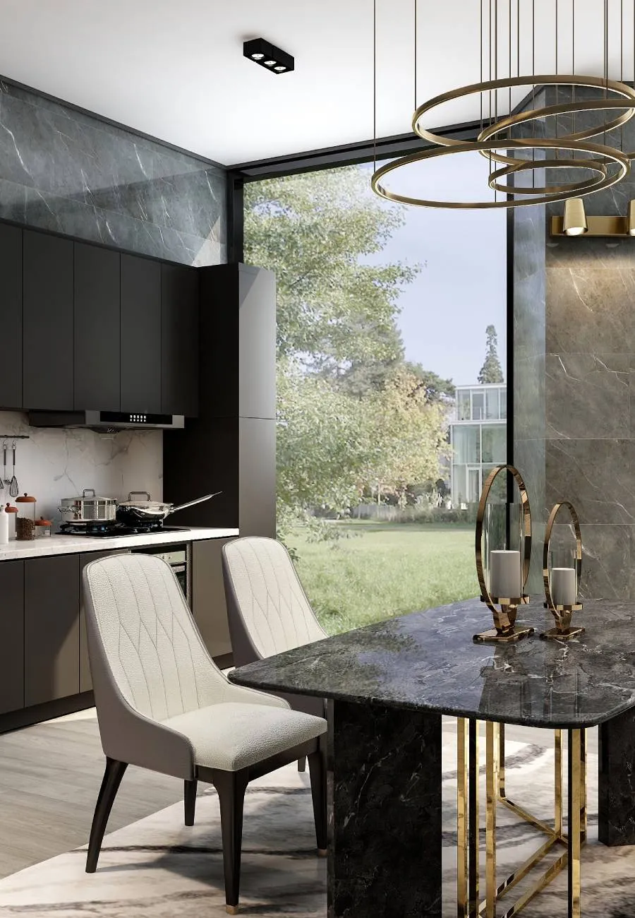 A modern kitchen and dining area with dark matte cabinetry, a marble backsplash, a dark marble dining table with cream upholstered chairs, gold ring pendant lights and floor-to-ceiling glass doors opening to a garden