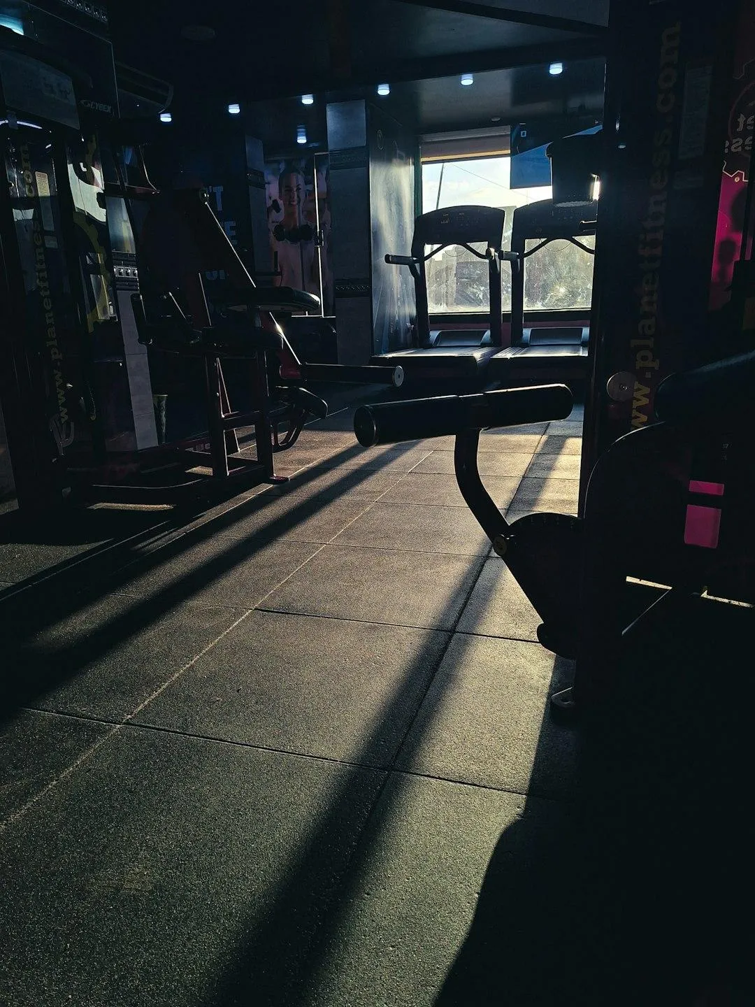 Un adulte s’entraîne dans une salle lumineuse, avec une lumière douce de lever de soleil d’un côté et une ambiance de fin de journée de l’autre, illustrant la question du meilleur moment pour s’entraîner.