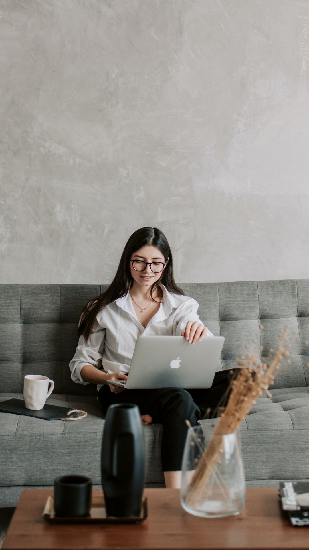 Woman working on a laptop in a calm, neutral space representing ongoing nervous system support and women’s healing memberships