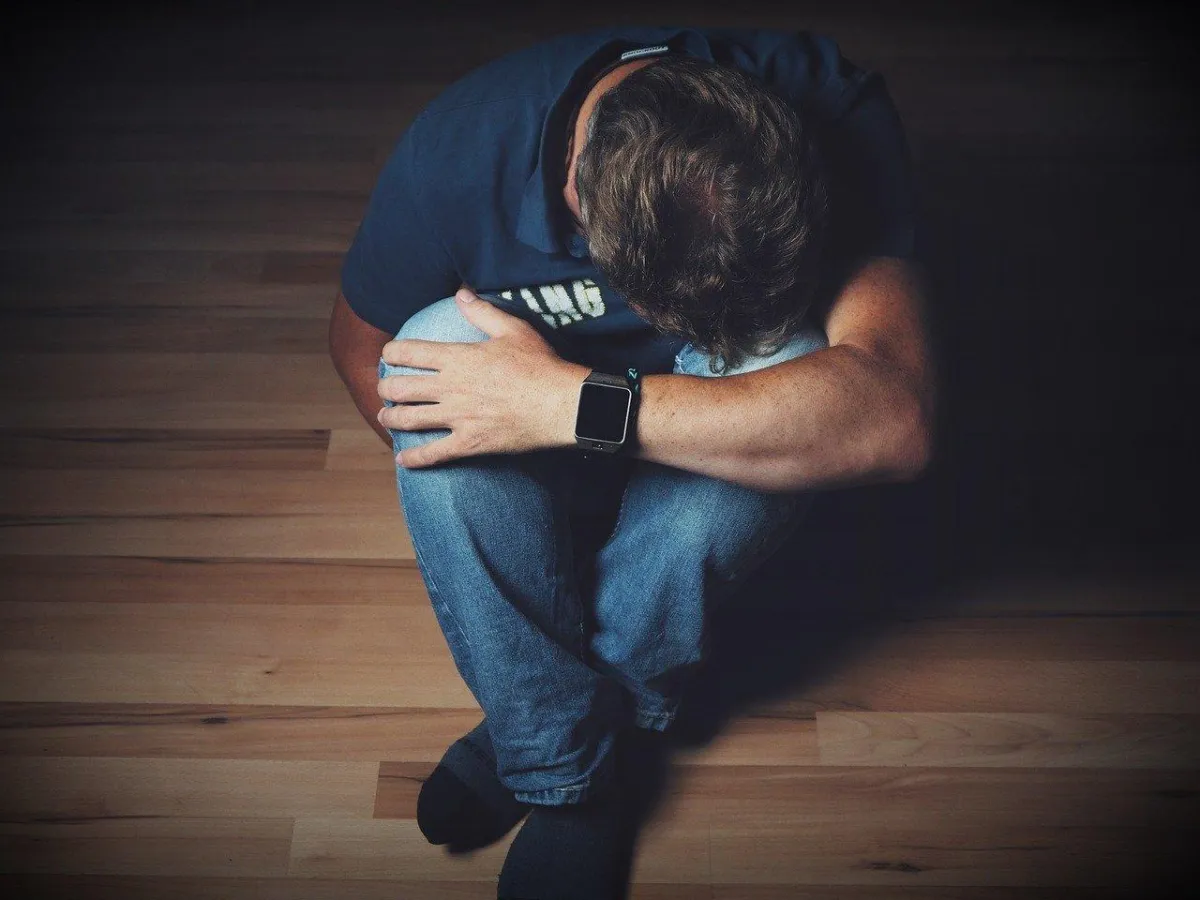 A man grimaces in discomfort, holding his stomach as he experiences belly pain.