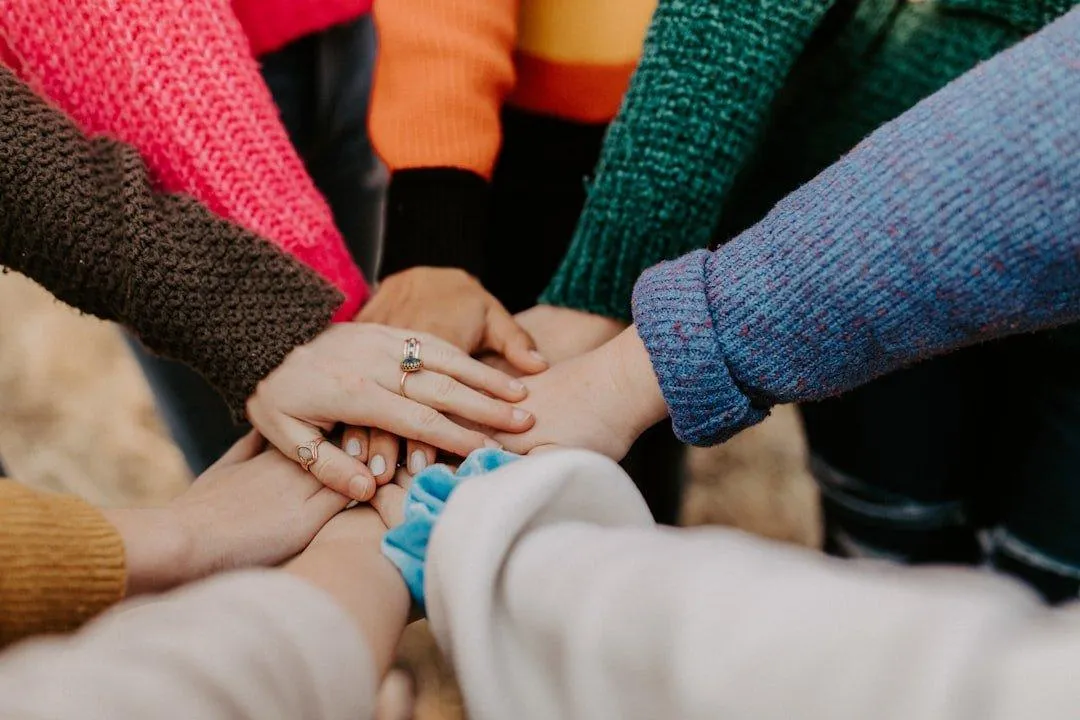 Hands of many people are united, forming a circle in a gesture of solidarity and togetherness.