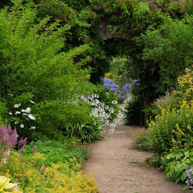 Garden path with established planting leading through a brick archway in Bromsgrove garden