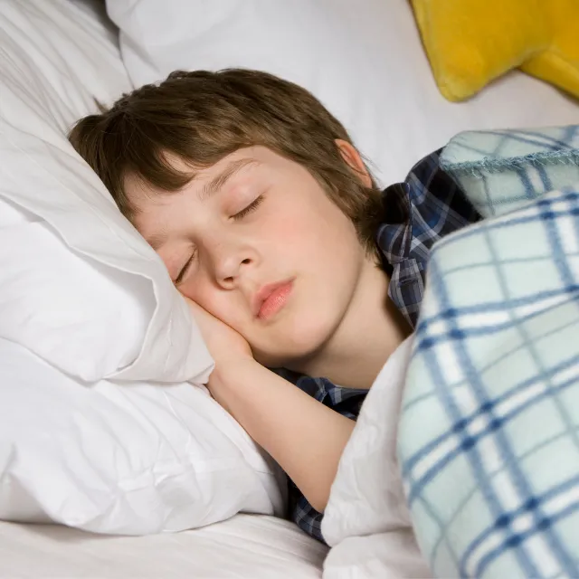 Child sleeping peacefully in bed, representing the importance of sleep, rest and emotional wellbeing for children and teenagers.