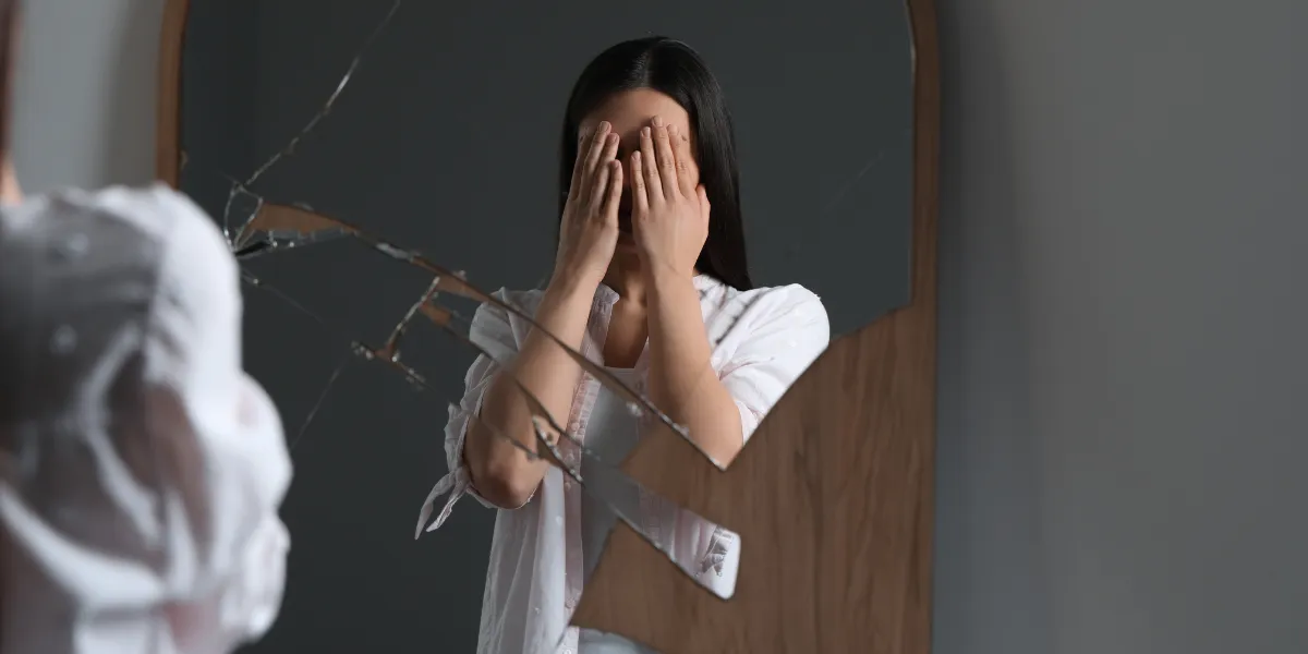 Young person looking thoughtfully at their reflection, illustrating self-esteem and self-image challenges.