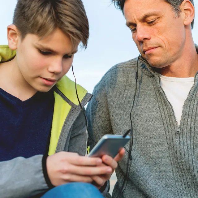 Father and son listening to music together, sharing quality time and strengthening their family connection through a shared interest.