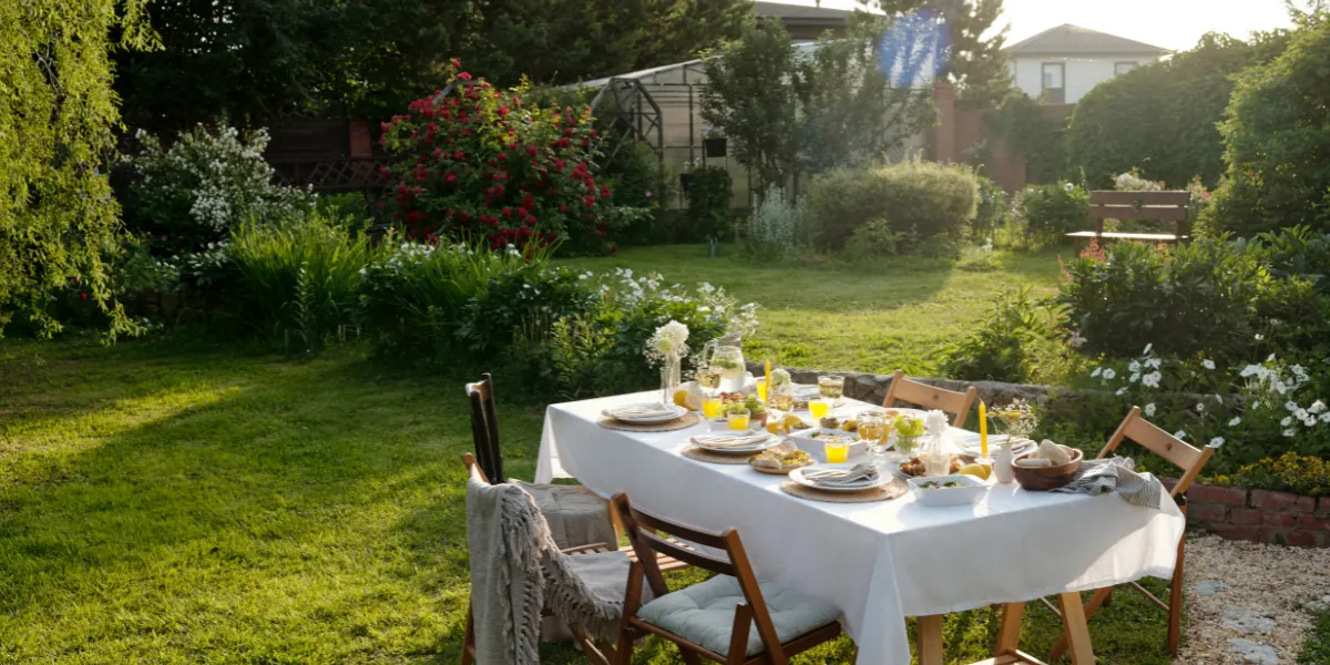 Outdoor dining table set for a summer meal surrounded by a colourful garden