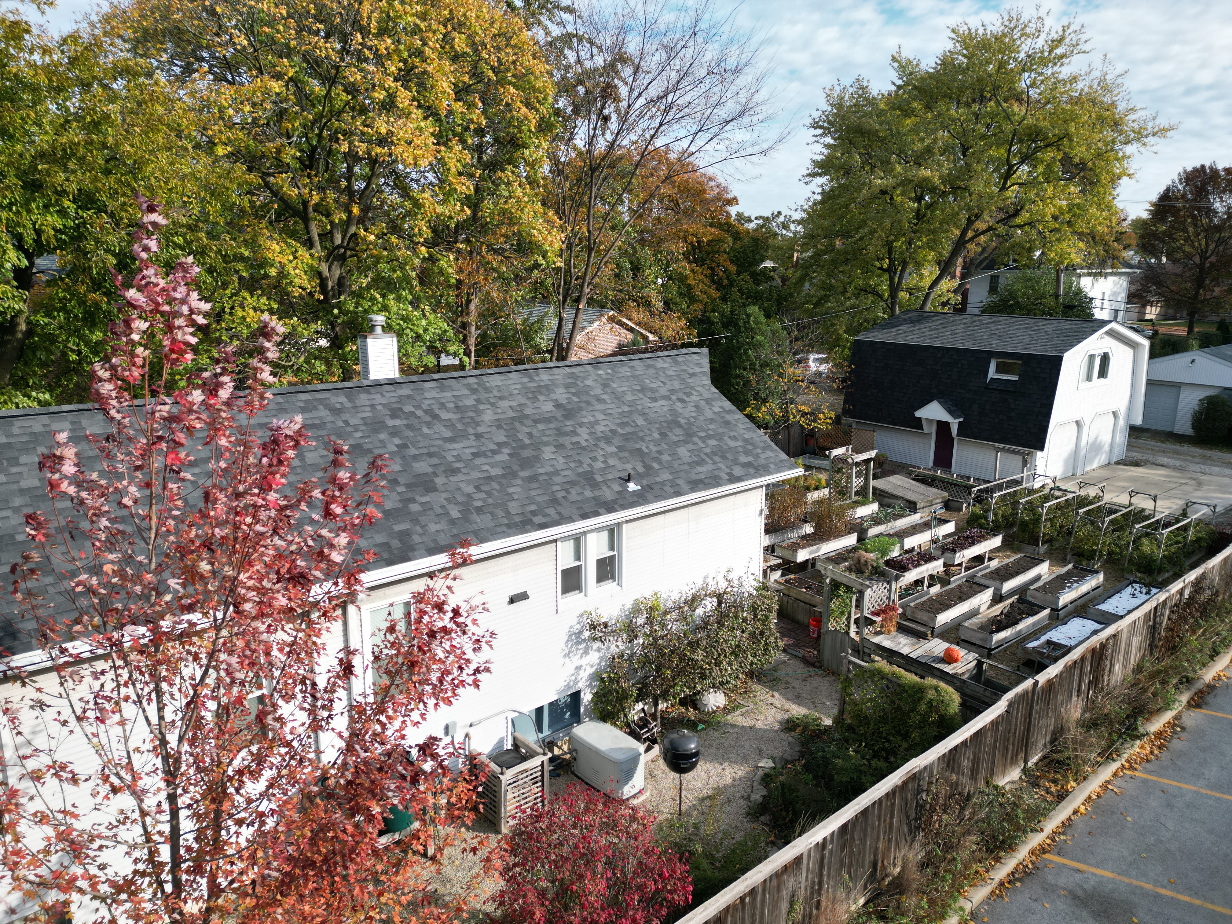 Malarkey Midnight Black shingle roof installed by Northwind Exteriors on a white home in Park Ridge, IL, featuring a mansard roof on the garage and careful work to protect the full edible garden in the backyard.