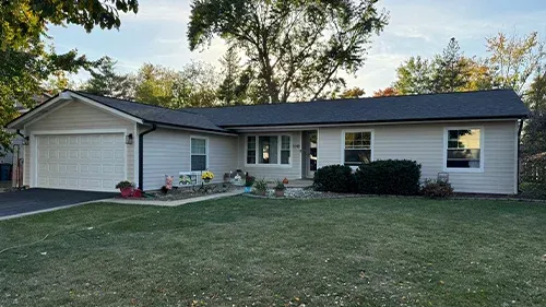 Cobblestone James Hardie siding with Arctic White trim, black soffit, fascia, and gutters, paired with a Malarkey Brilliant Black roof, installed on a home in Elk Grove Village, IL by Northwind Exteriors.