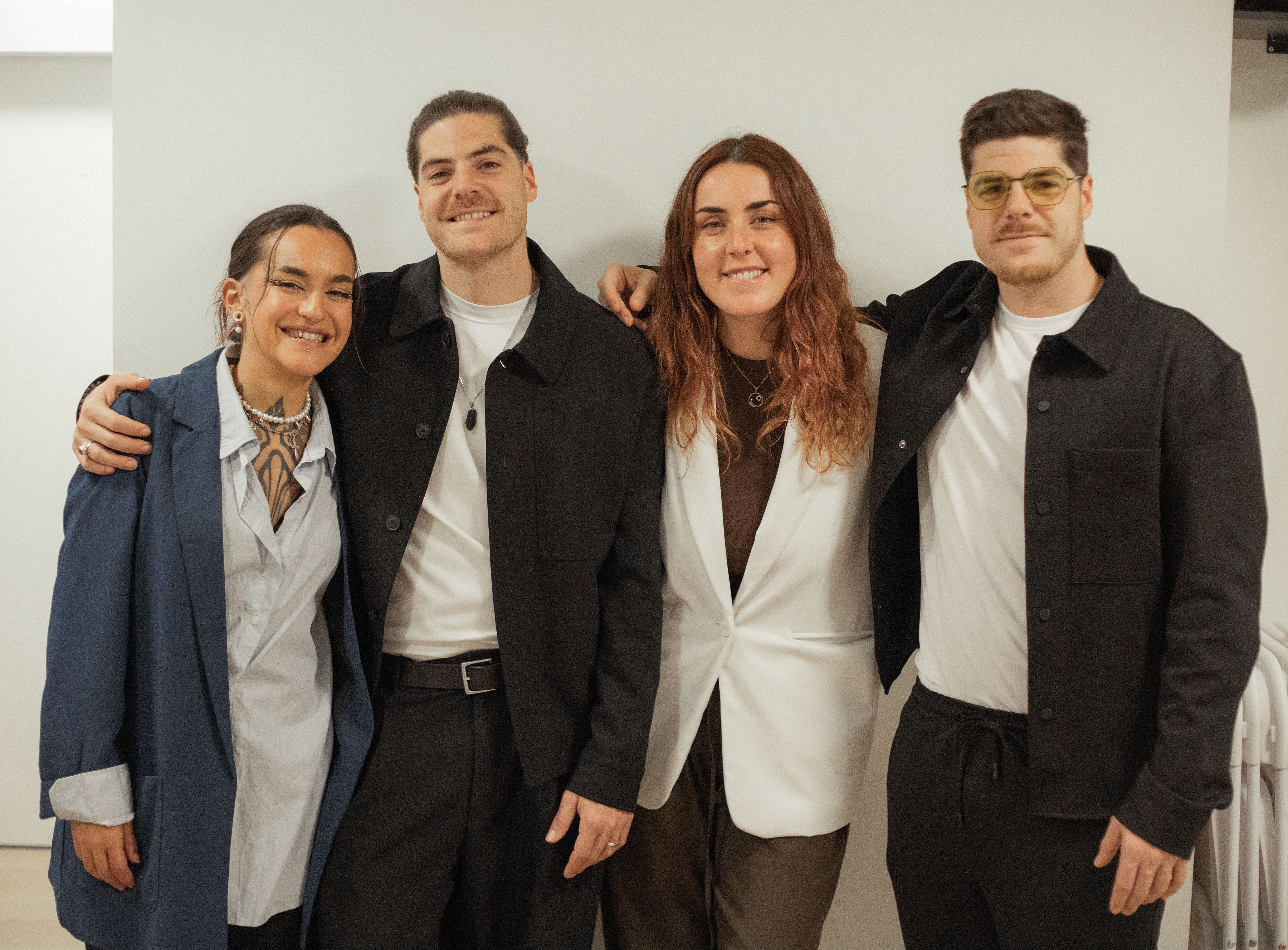 A modern convention center exterior with glass walls, lush greenery, and people gathering outside, some checking event schedules on their phones, others chatting in small groups. The scene is bright, welcoming, and urban, emphasizing accessibility and excitement for the upcoming event.