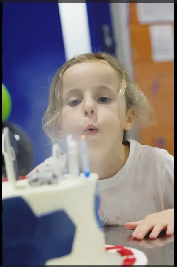 A birthday cake with candles being blown out by a child