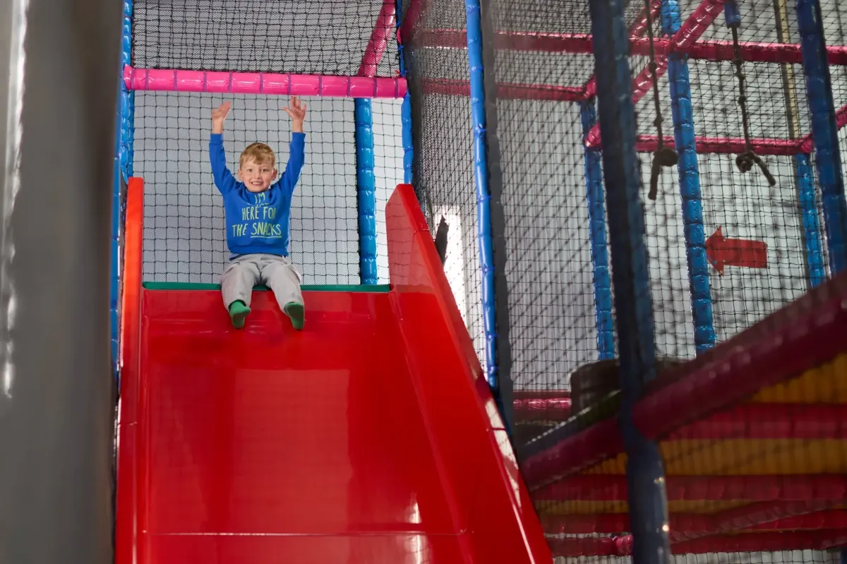 Child ready to slide down the big en playing in the vibrant Giant Ball Arena at Party and Play Funhouseed drop slide at Party and Play Funhouse