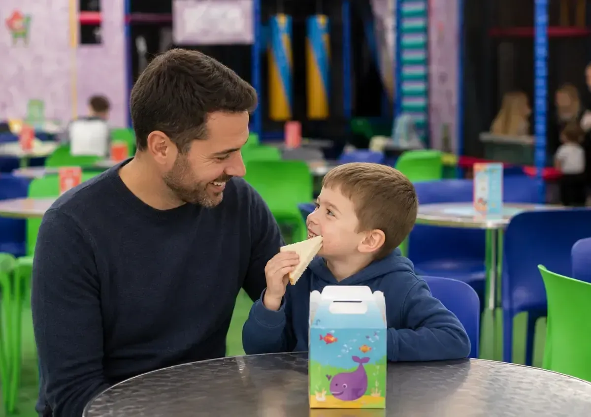 Father and son enjoying a picnic box in the play centre