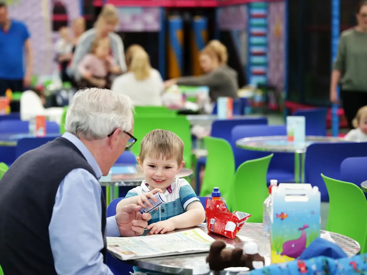 Grandparent enjoying a break at the onsite cafe while giving a toddler an ice-cream