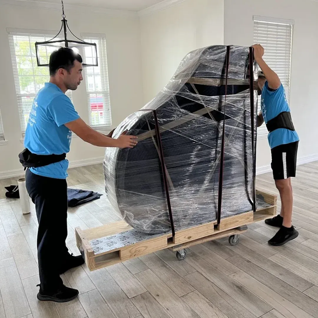 Professional movers safely transporting a wrapped piano during a residential move in Connecticut