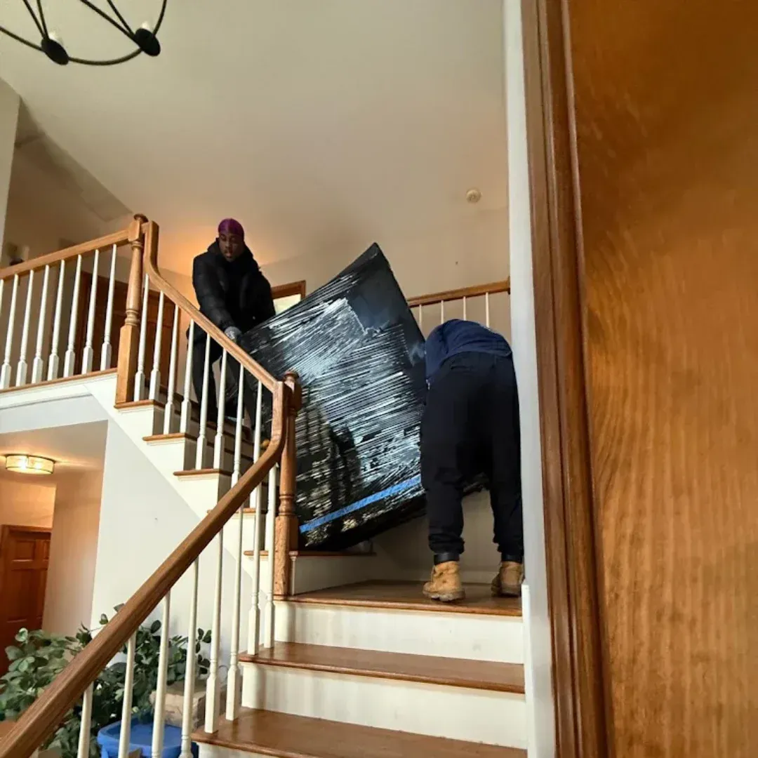 Professional apartment movers carrying large furniture upstairs during a residential move in Connecticut