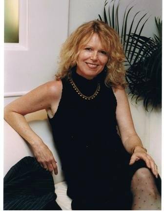 Dot Harvey laughing with her grandchildren in a sunlit backyard, surrounded by blooming flowers and greenery. The candid moment captures joy and warmth, with everyone smiling and embracing, reflecting the love and closeness of family bonds.