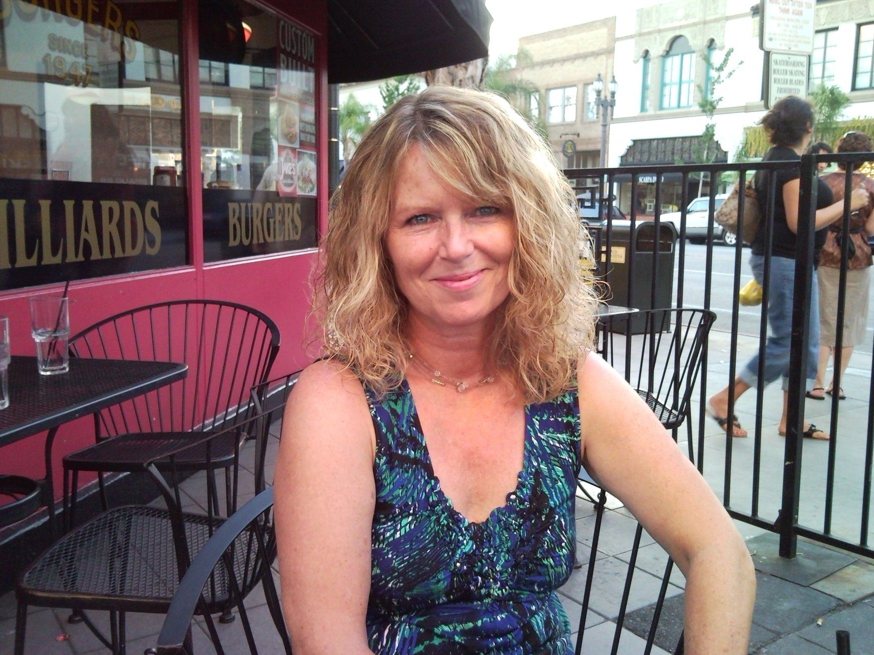 Dot Harvey laughing with her grandchildren in a sunlit backyard, surrounded by blooming flowers and greenery. The candid moment captures joy and warmth, with everyone smiling and embracing, reflecting the love and closeness of family bonds.