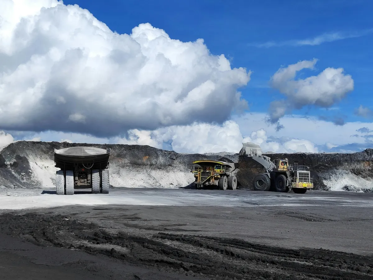 Large haul truck and front-end loader at an open-cut mining site under a bright blue sky, representing earthmoving equipment inspections.
