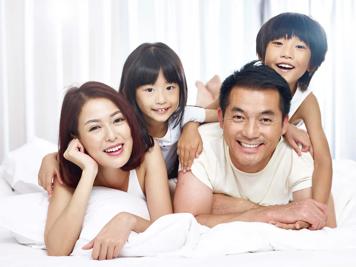 Happy Asian family smiling and showing healthy teeth at Kong Dental Surgery in Singapore.