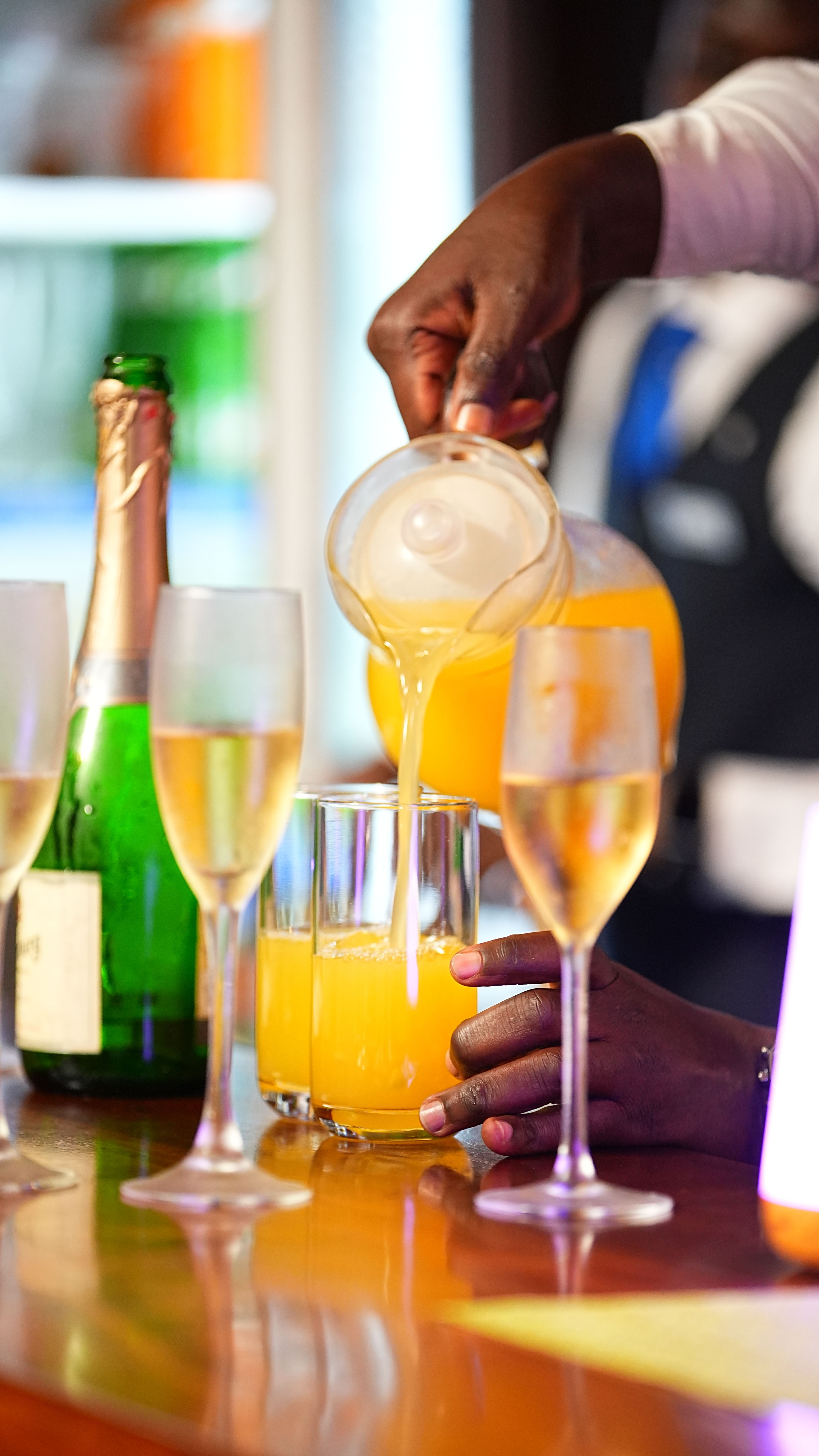 Hand pouring mimosa into glasses