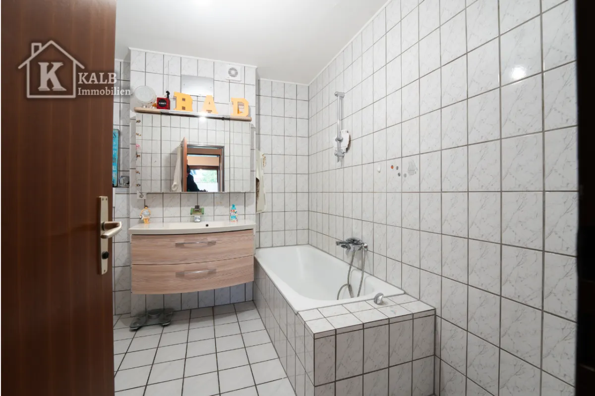 Gefliestes Badezimmer der Eigentumswohnung in Niederwerrn mit Badewanne und Waschtisch