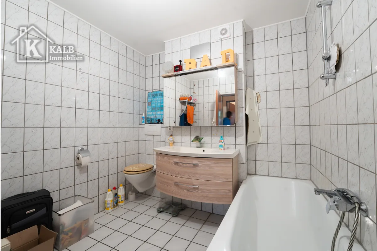 Gefliestes Badezimmer der Eigentumswohnung in Niederwerrn mit Badewanne, WC und Waschtisch