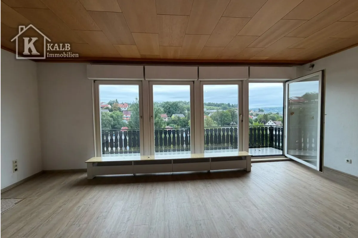 Großzügiger Wohnbereich mit bodentiefen Fenstern und Zugang zum Balkon
