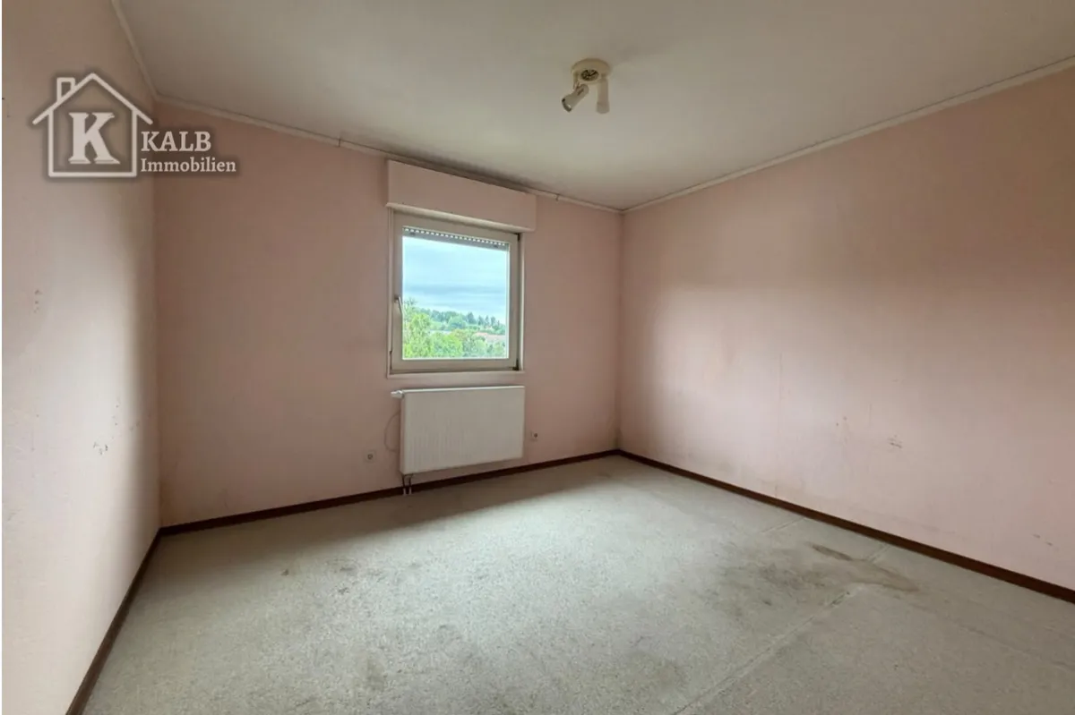 Leerstehendes Zimmer mit Fenster und Blick ins Grüne in der Immobilie