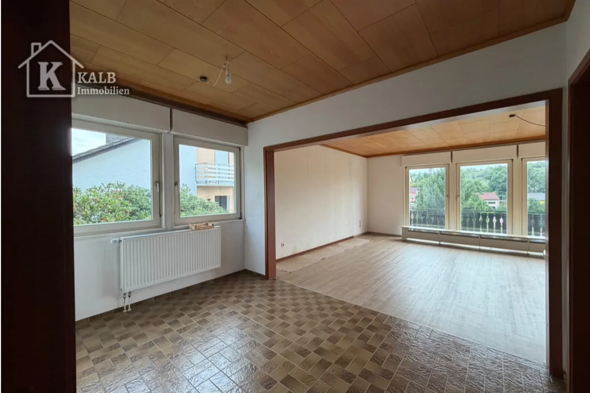 Offener Wohn- und Essbereich mit großen Fensterflächen und Balkonblick