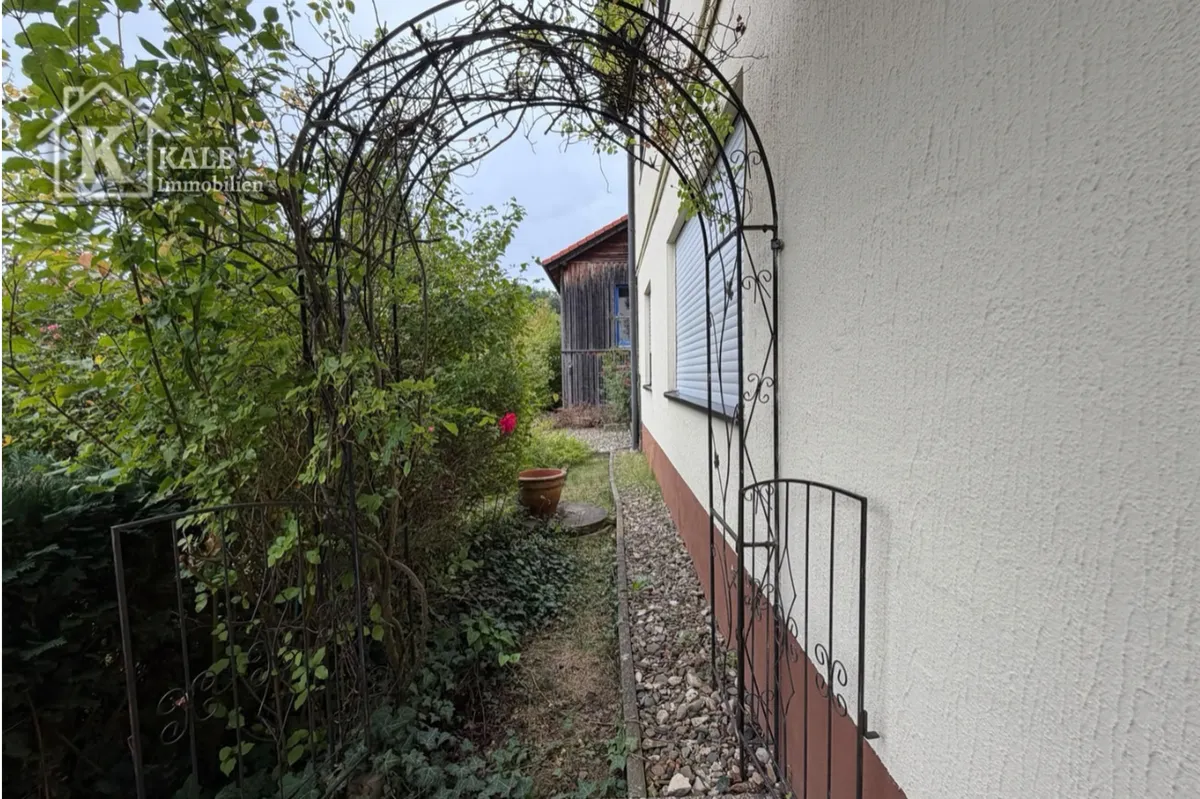 Seitlicher Gartenweg am Zweifamilienhaus in Eltmann mit bewachsenem Rosenbogen