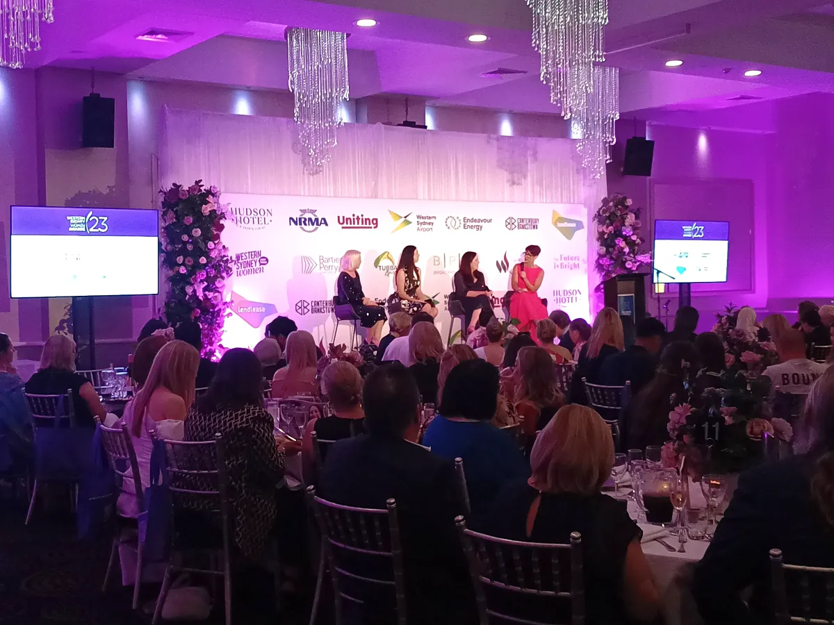 Gala stage AV with dual LED screens, purple wash lighting, integrated floral media wall, and professional PA speakers