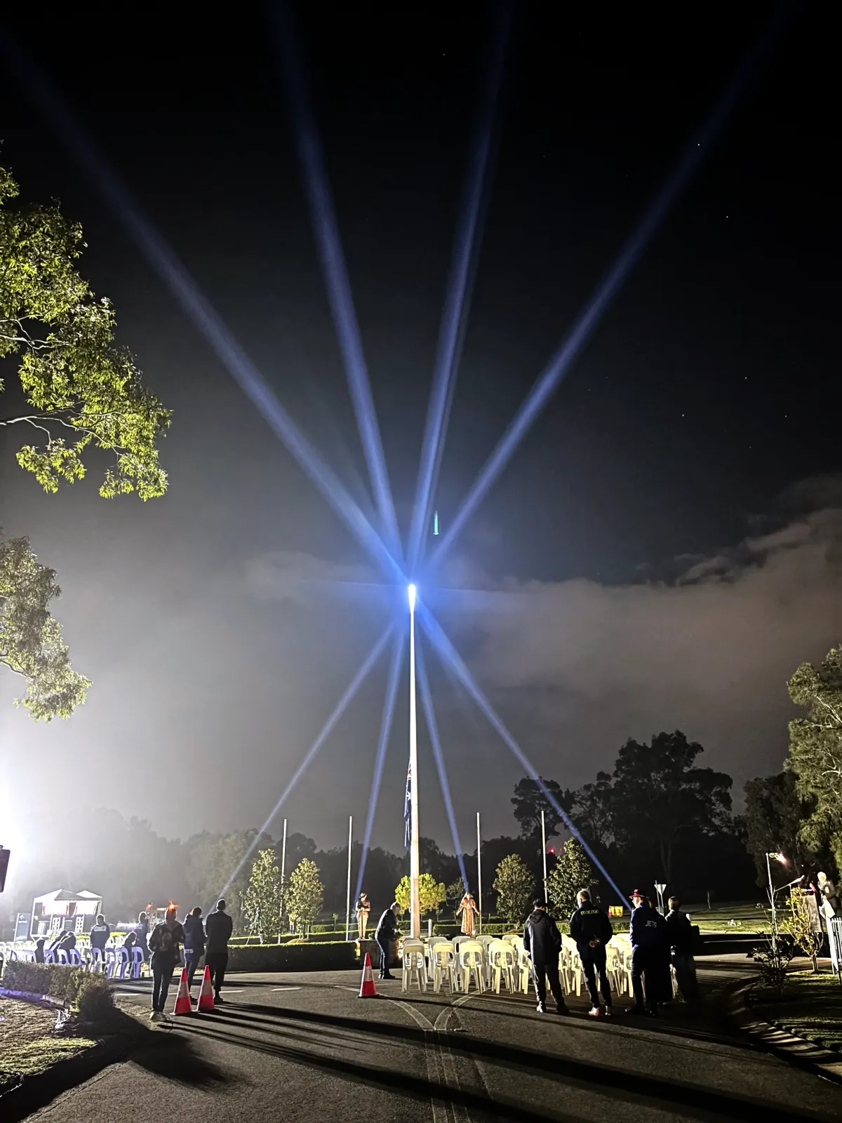 High-powered LED beam lighting fixtures creating a dramatic blue ray effect around a central flag pole at night