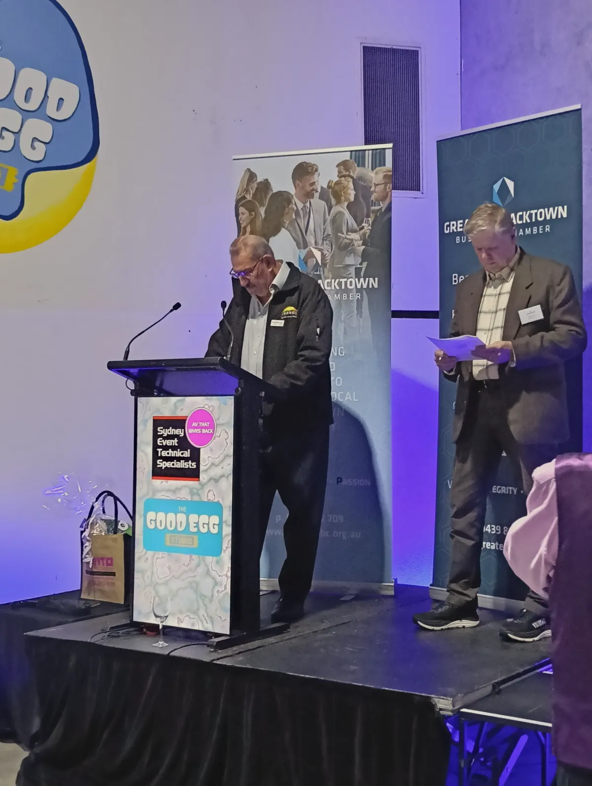 Professional corporate lectern with dual gooseneck microphones on a skirted mobile stage platform with pull-up banner