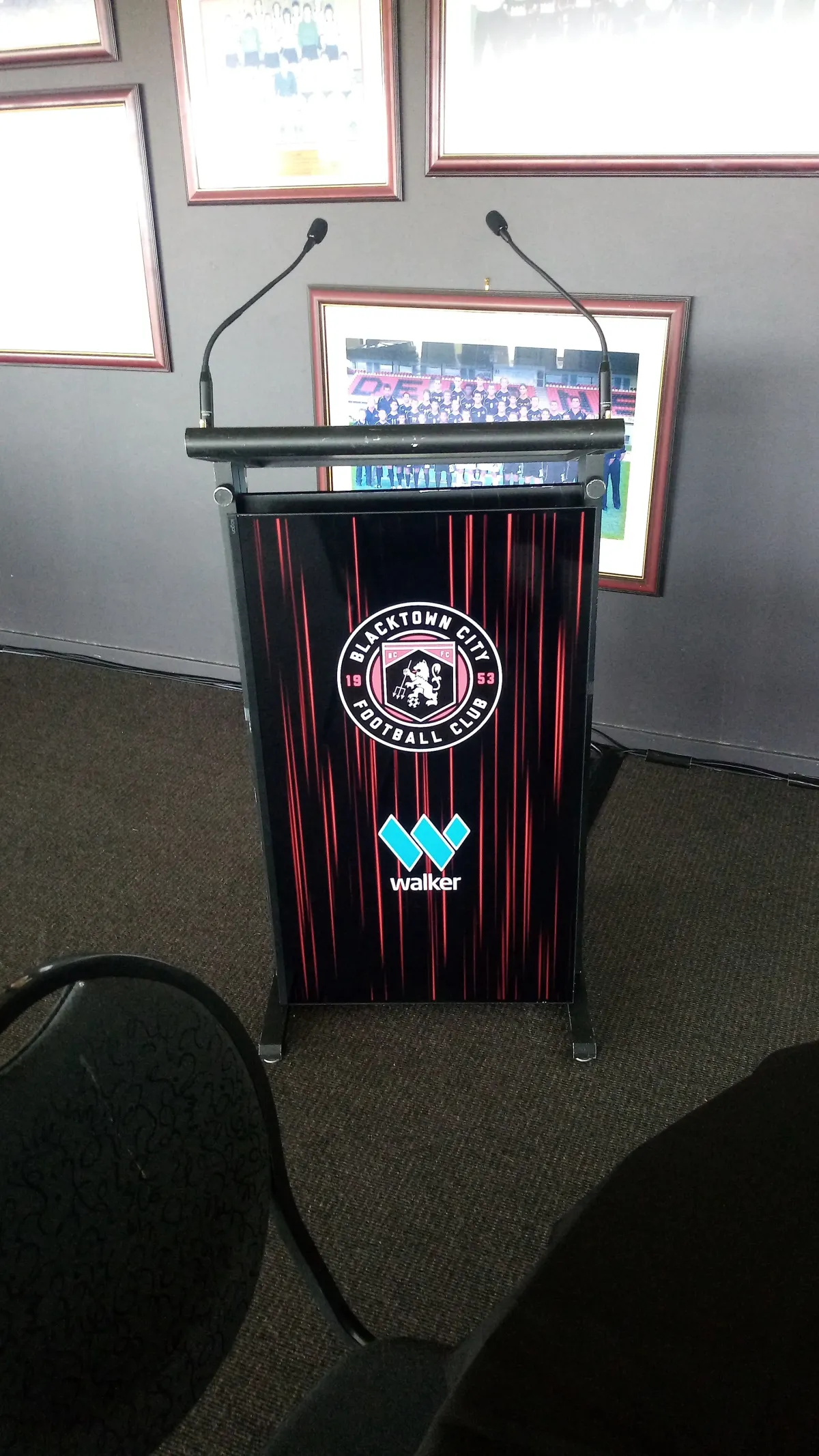 Digital lectern with integrated display branding and dual gooseneck microphones for a corporate sports club event