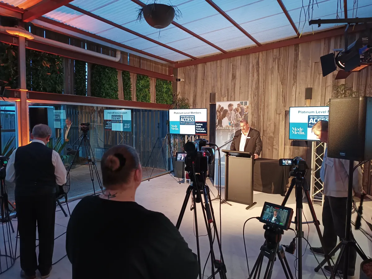 Multi-camera live stream setup with professional video cameras on tripods, LED monitors, and a black lectern