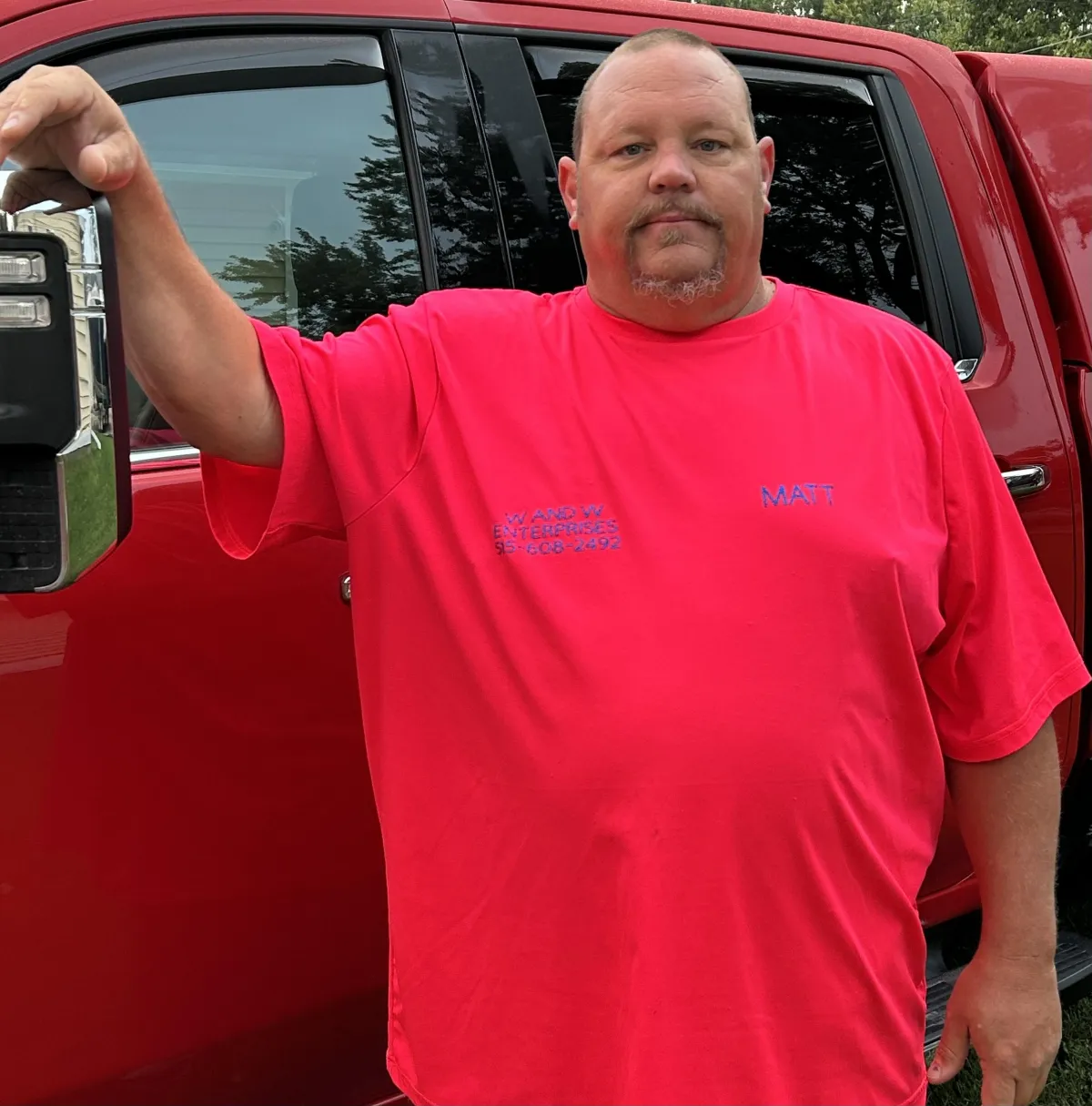 Employee in branded W and W Enterprises shirt beside company truck.
