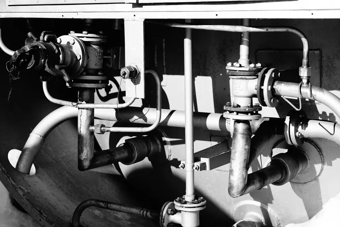 Close-up of industrial plumbing system with metal pipes, valves, and connectors in a mechanical facility.