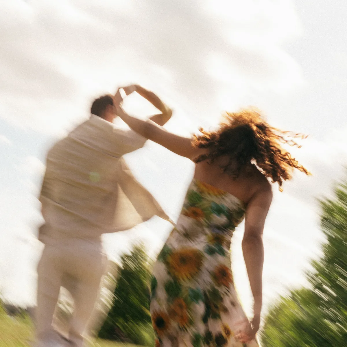 A man and a woman dancing and spinning together in a field.