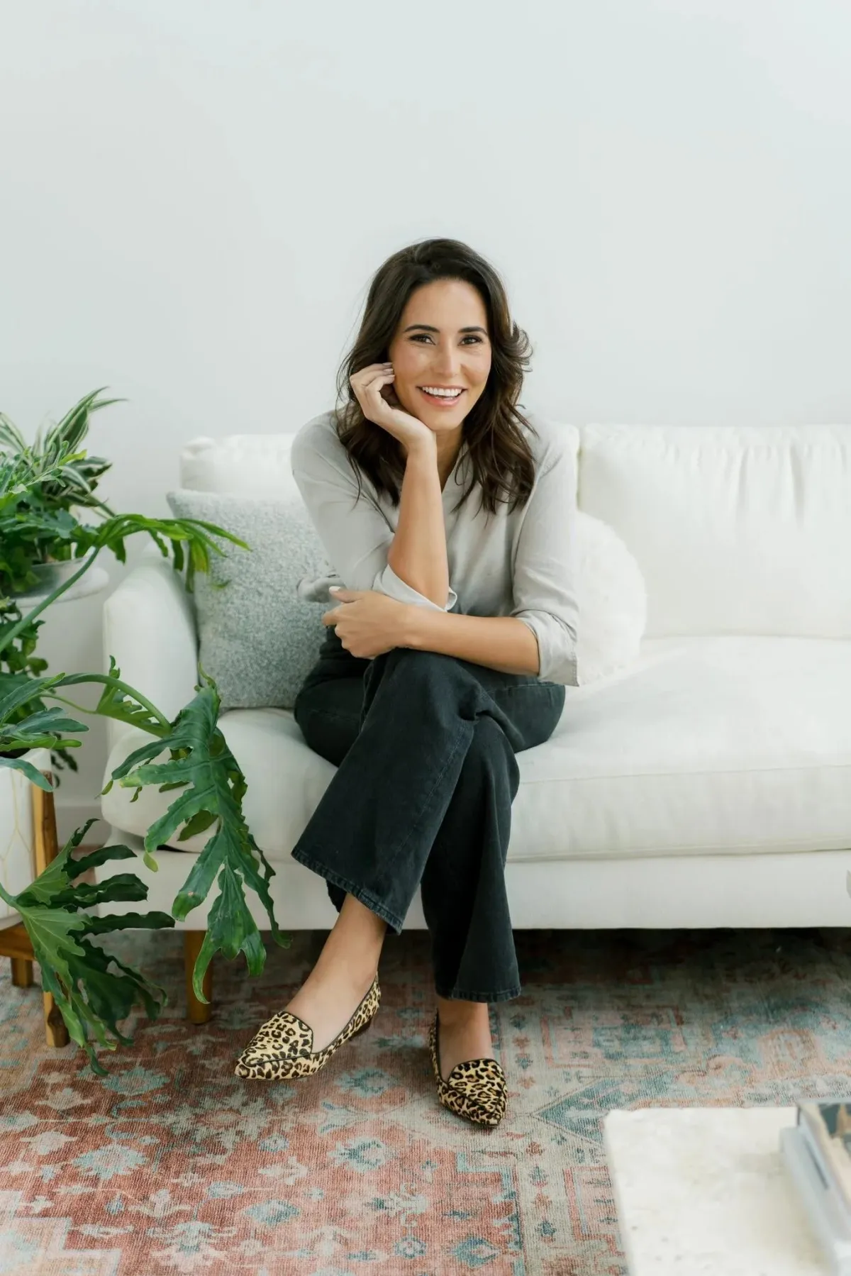 Eva McCage, licensed therapist at Outliers Psychotherapy, sitting on a white couch in a peaceful therapy setting