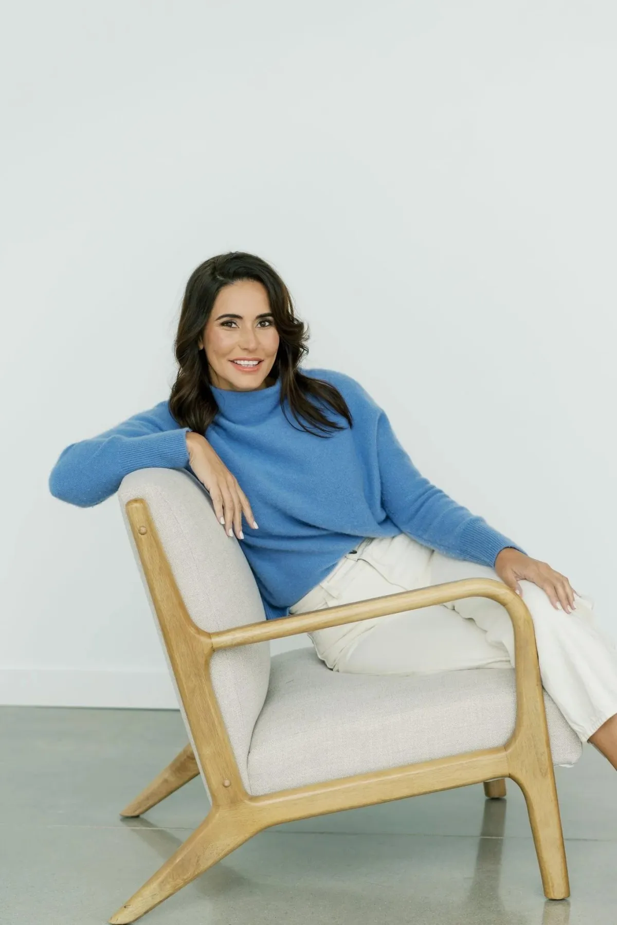 Eva McCage in a blue sweater, seated in a modern armchair, offering solution-focused therapy services