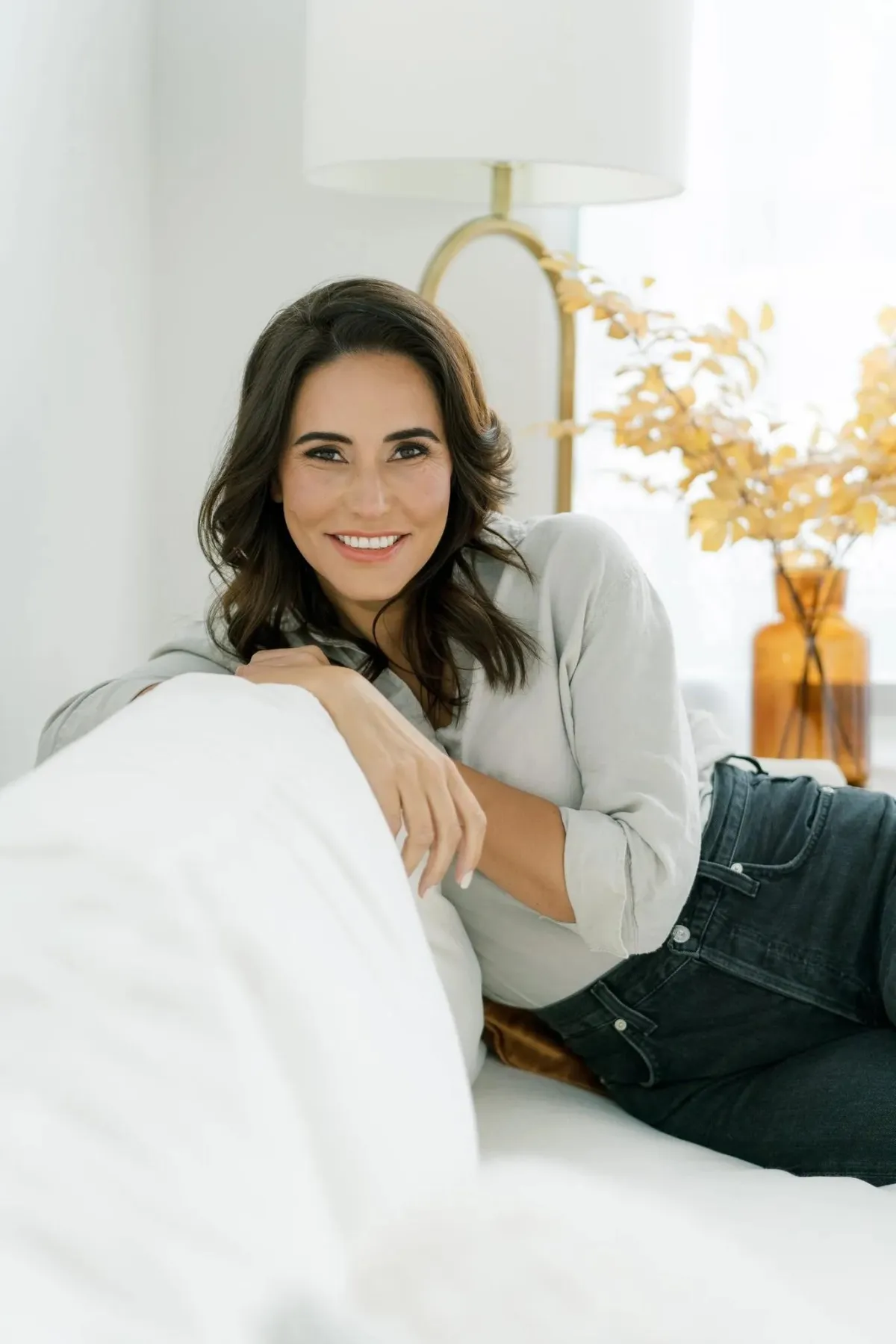 Eva McCage, therapist at Outliers Psychotherapy, smiling warmly in a peaceful therapy room with soft lighting