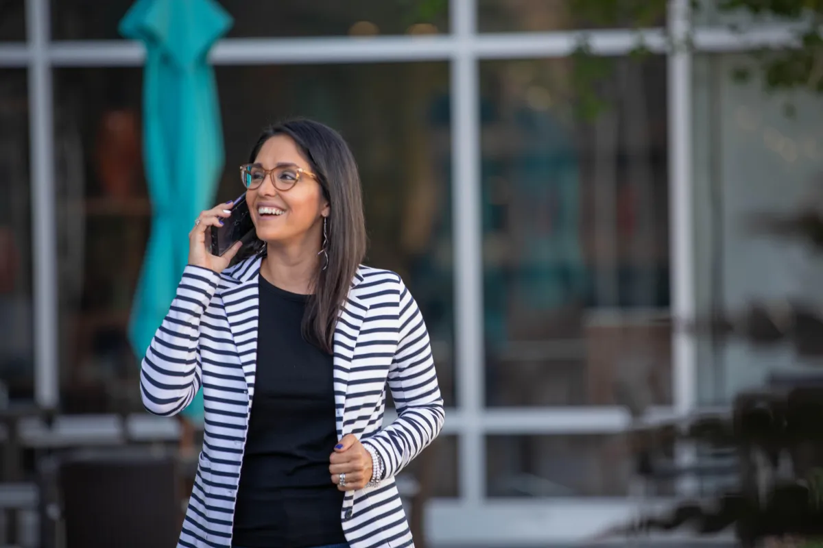 Oficina moderna con pared azul, muebles blancos minimalistas y recepcionista amigable saludando a un visitante.