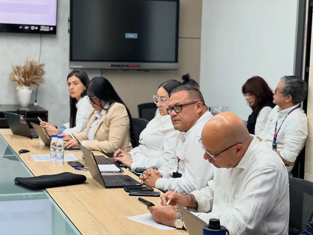 Wind turbines illuminated red at dusk over water.