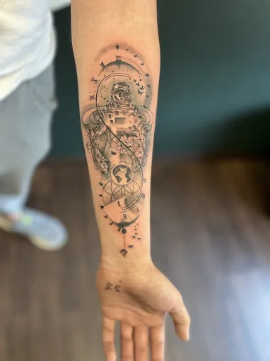 Close-up of a detailed arm sleeve tattoo with various elements