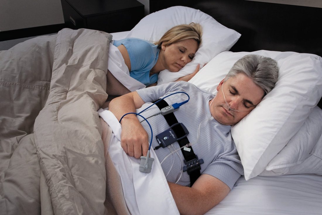 A person using a home sleep study device in bed