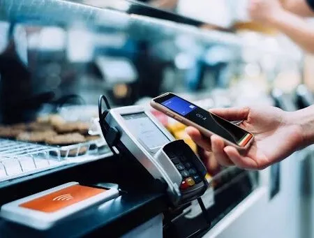 Customer tapping a smartphone on an NFC device at a counter