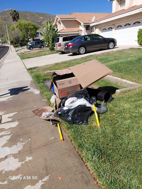 Residential junk removal by Rabbits Services, with discarded furniture and garbage bags in a front yard in Lake Elsinore, Temecula, and Riverside