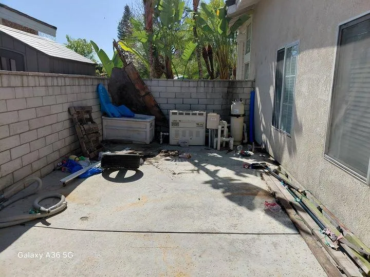 Yard waste removal by Rabbits Services, with a backyard full of green debris including leaves and branches in Lake Elsinore, Temecula, and Riverside