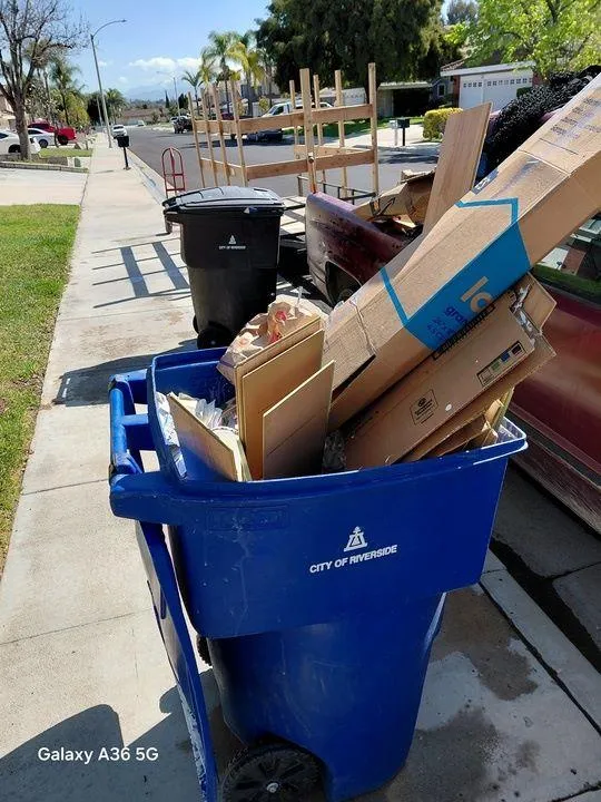 Construction and demolition debris removal by Rabbits Services, with a blue bin full of cardboard and construction waste in Menifee, Temecula, and Riverside