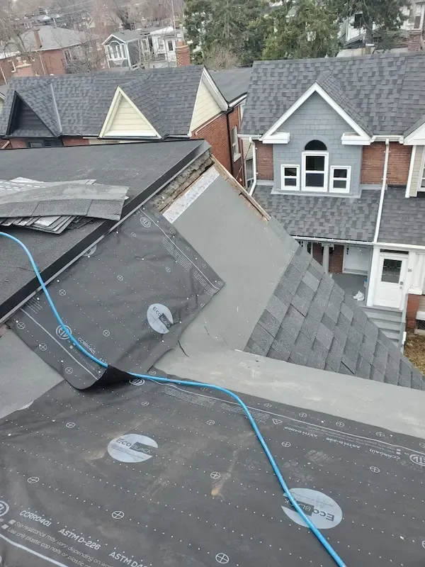 A-OK Roofing installation in progress on a residential home in Toronto, showcasing a complex roof retrofit transitioning between a flat roof system and a steep-slope asphalt shingle roof. High-quality black synthetic roofing underlayment is secured to the decking, preparing for final weather-resistant materials. Demonstrates expert flat-roof and shingle installations tailored for harsh Ontario seasons across East York and the GTA.